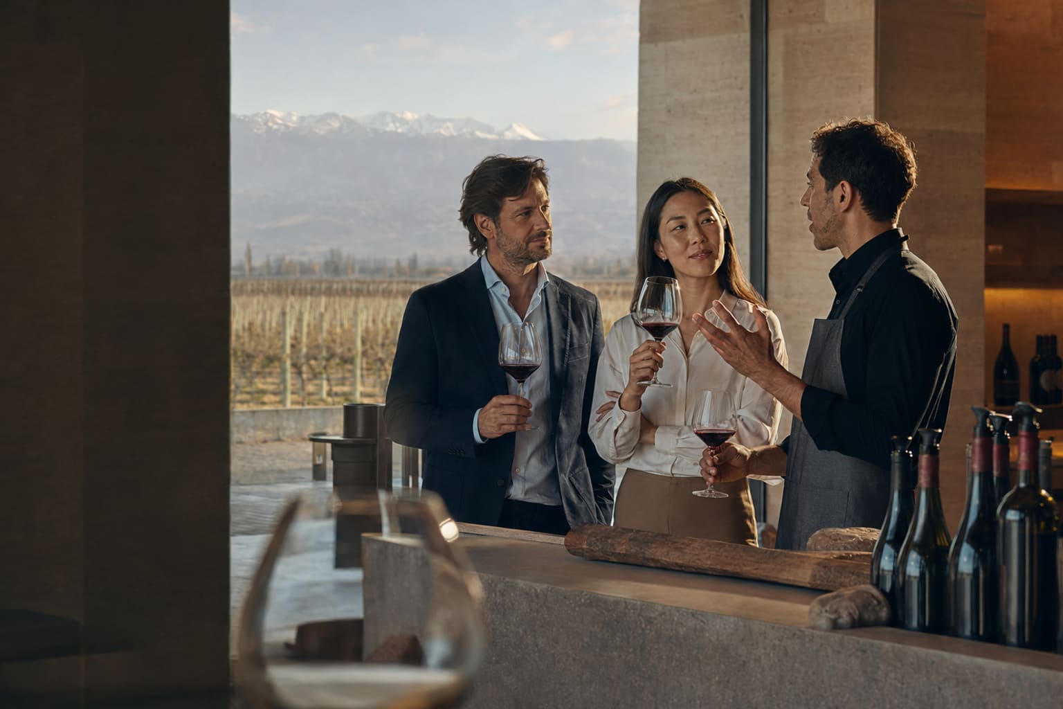 Profesionales de una bodega de Mendoza conversando sobre vino con copas y viñedos al fondo