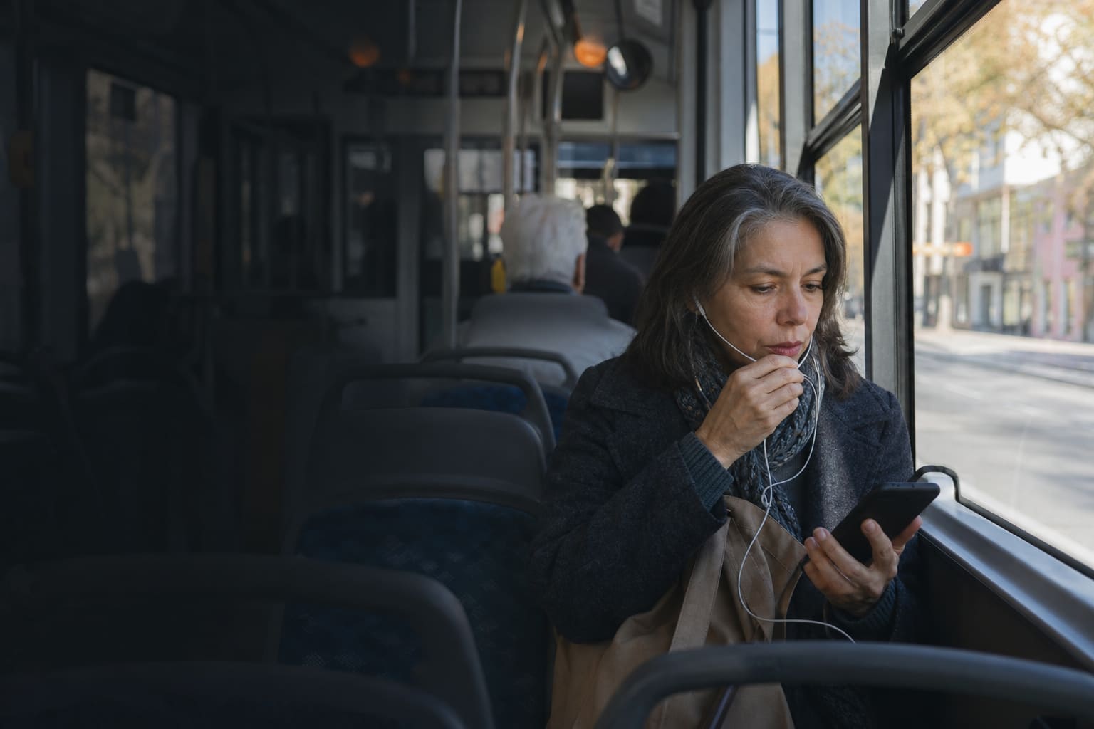 Adulta practicando pronunciación con una aplicación de inglés durante un viaje en colectivo