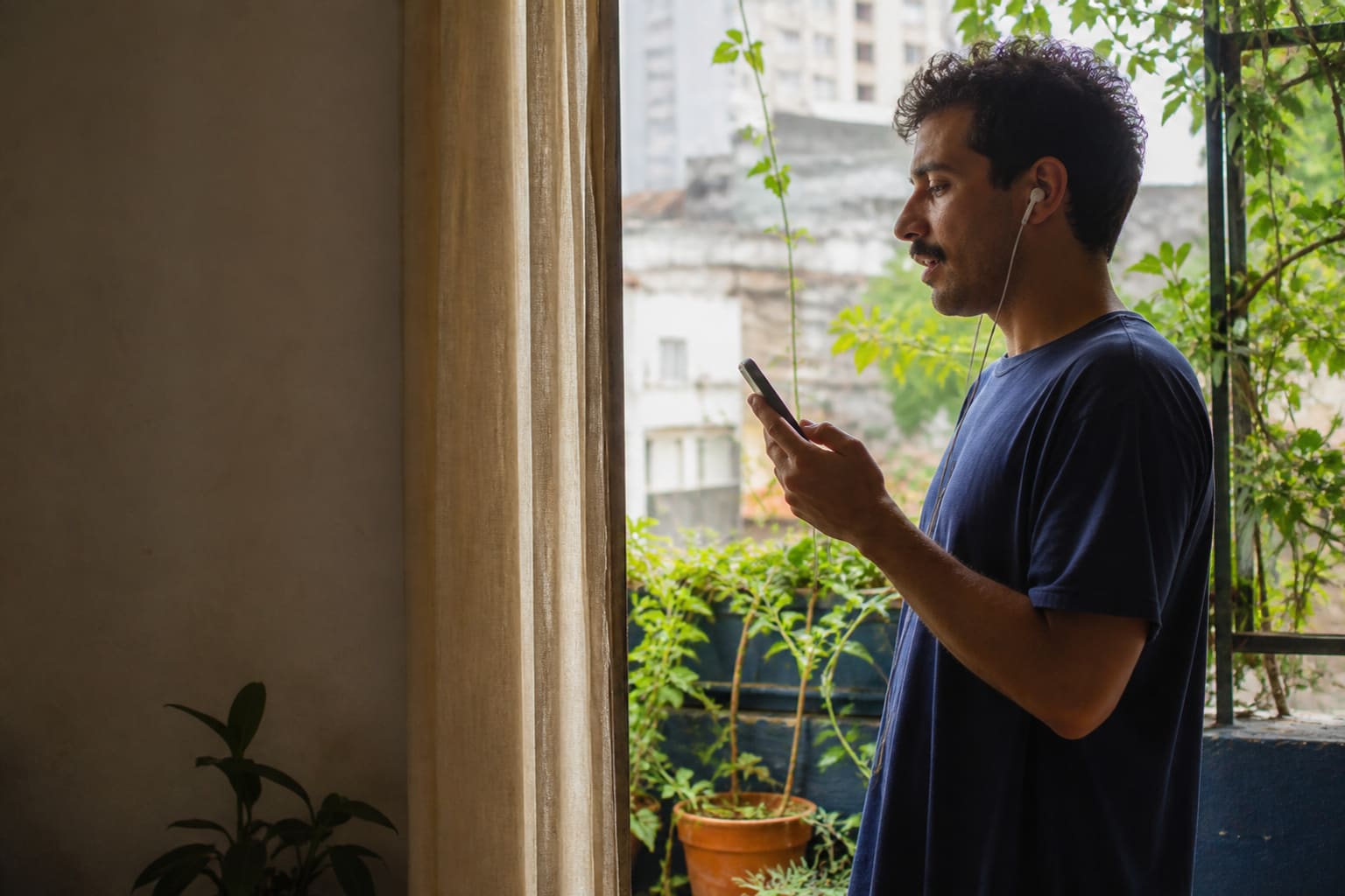 Brasileiro praticando espanhol junto a uma janela em um apartamento de São Paulo