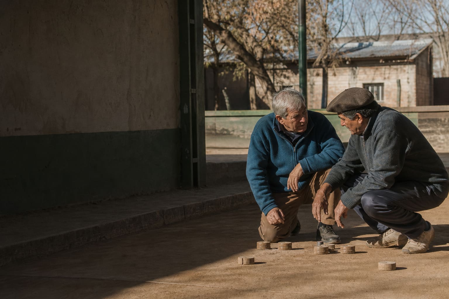 Older residents discussing a play at a neighborhood tejo court in Argentina