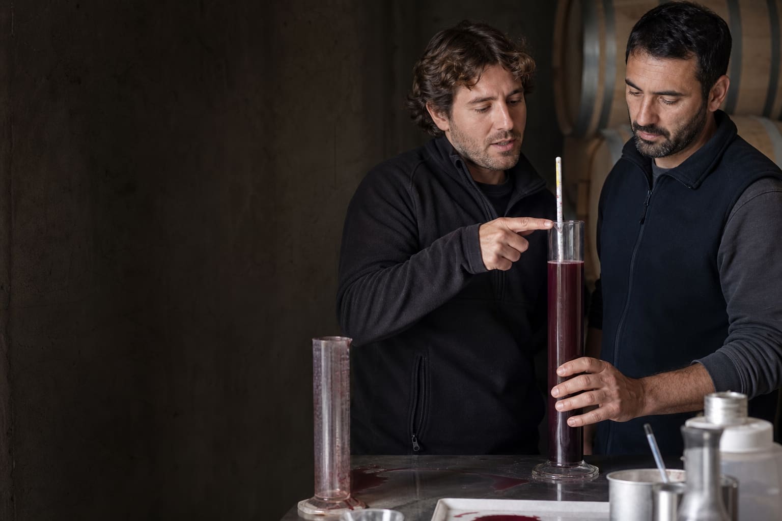 Wine professionals discussing must density in Spanish at a Mendoza winery laboratory