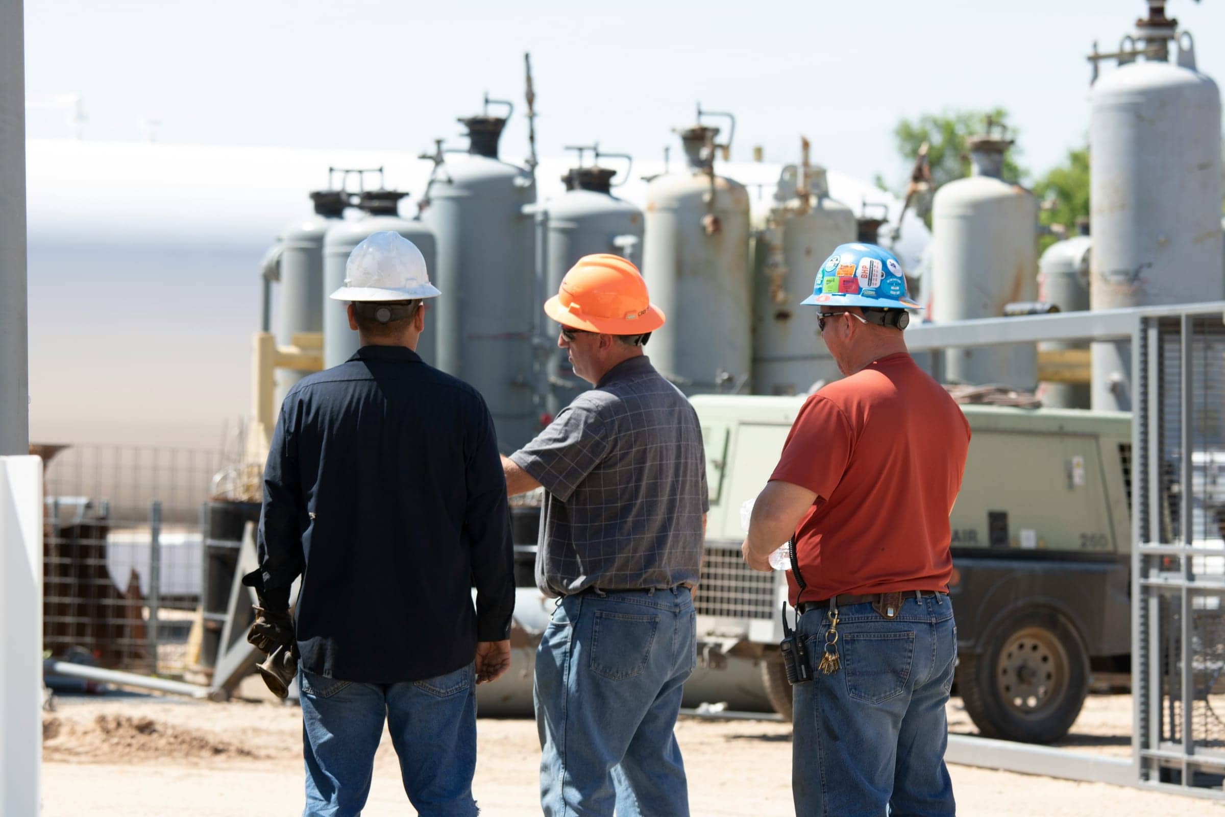 Trabajadores industriales con cascos de seguridad en sitio minero y oil & gas usando inglés técnico